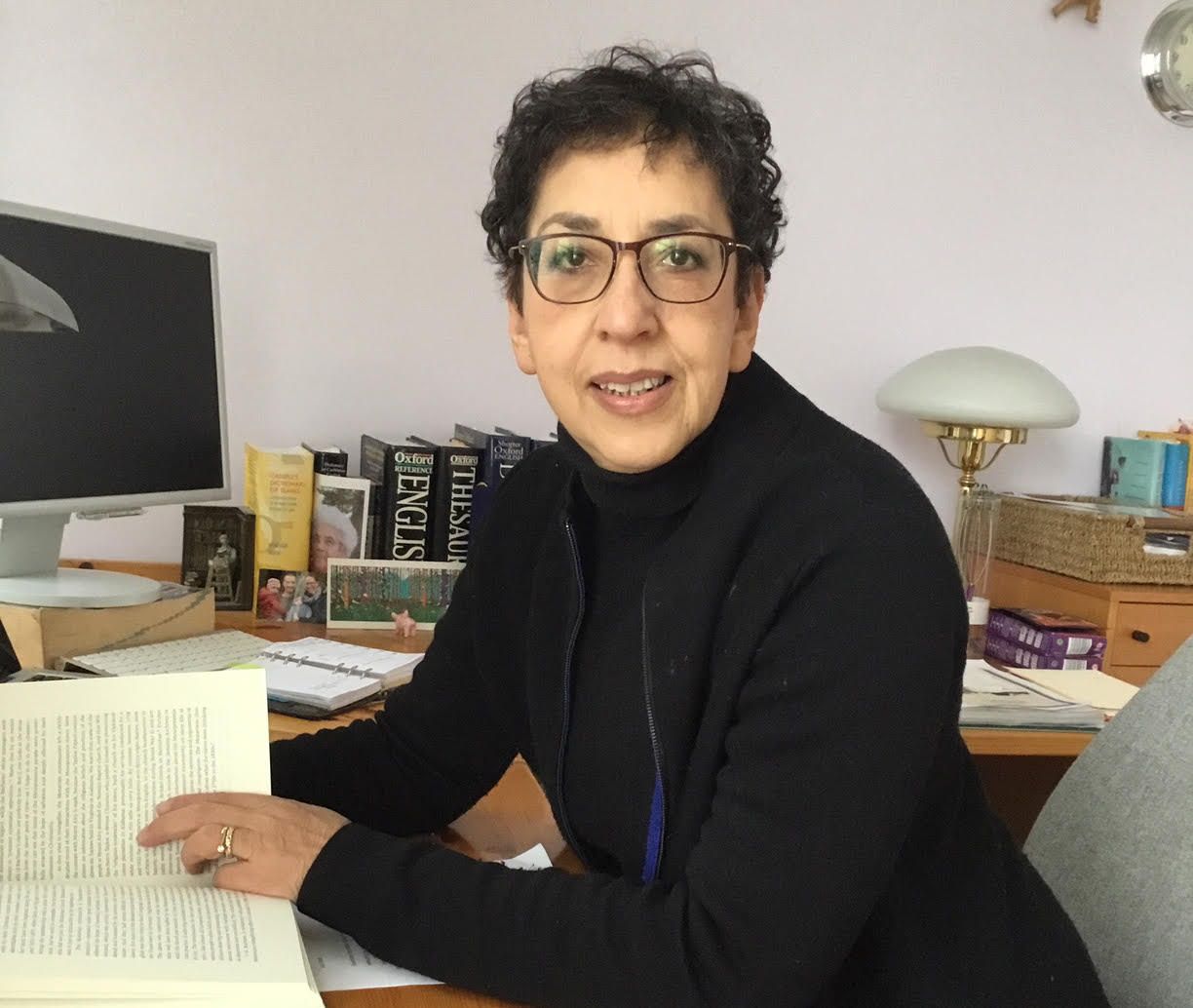writer at her desk with an open book.